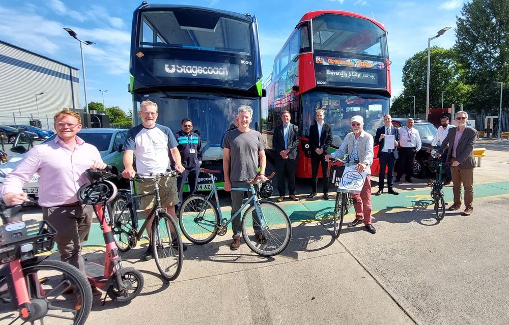 Signatories of the letter stand in front of two buses and a taxi. Pedestrians, scooterists and cyclists are seen in the image