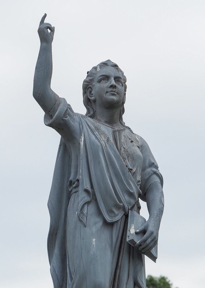 Detail of the figure on the top of the monument. One hand holds a book and the other points upwards.