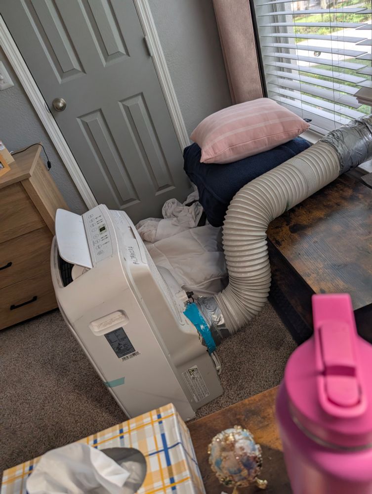 A portable AC unit with a hose out of the window