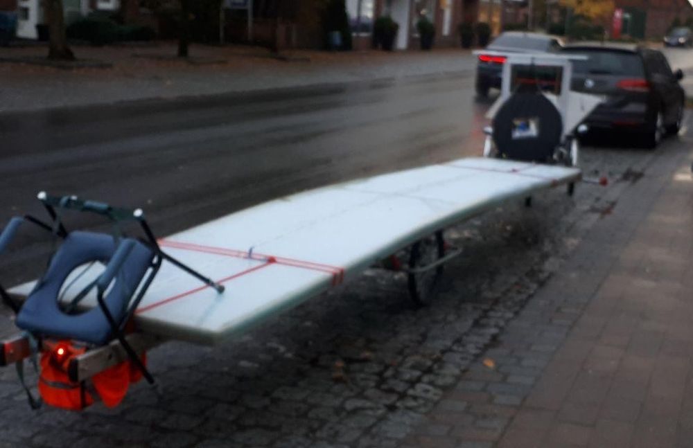 Ein Fahrradanhänger mit langen, hellen Kunststoffplatten.