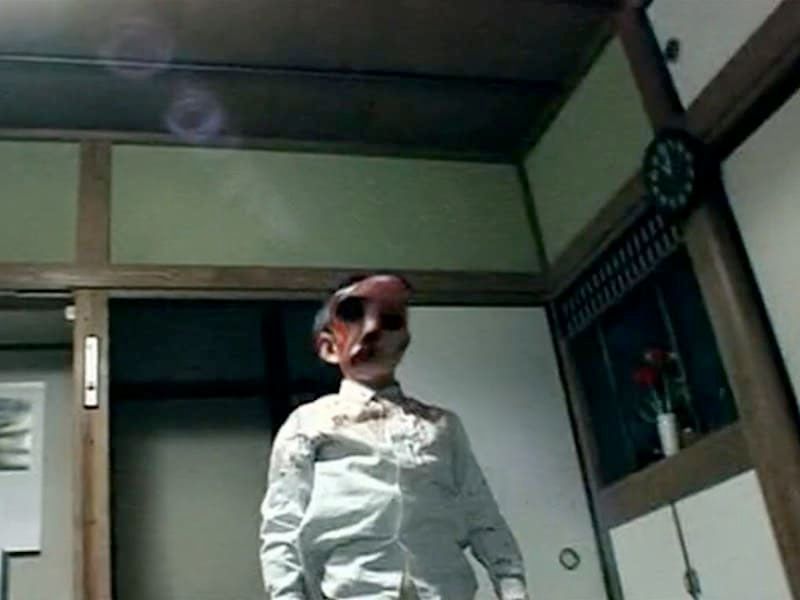A still from Noroi The Curse, showing a child with a distorted face.