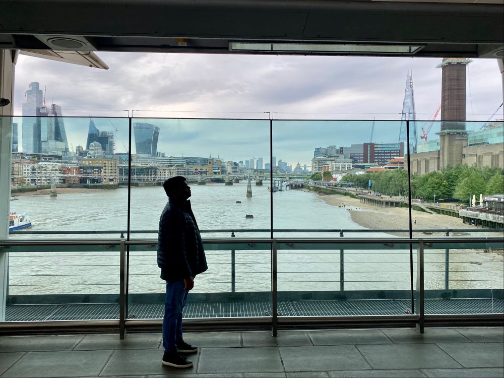 View of a silhouetted man standing on Blackfriars Station platform above the Thames with the view down the river towards the city. 