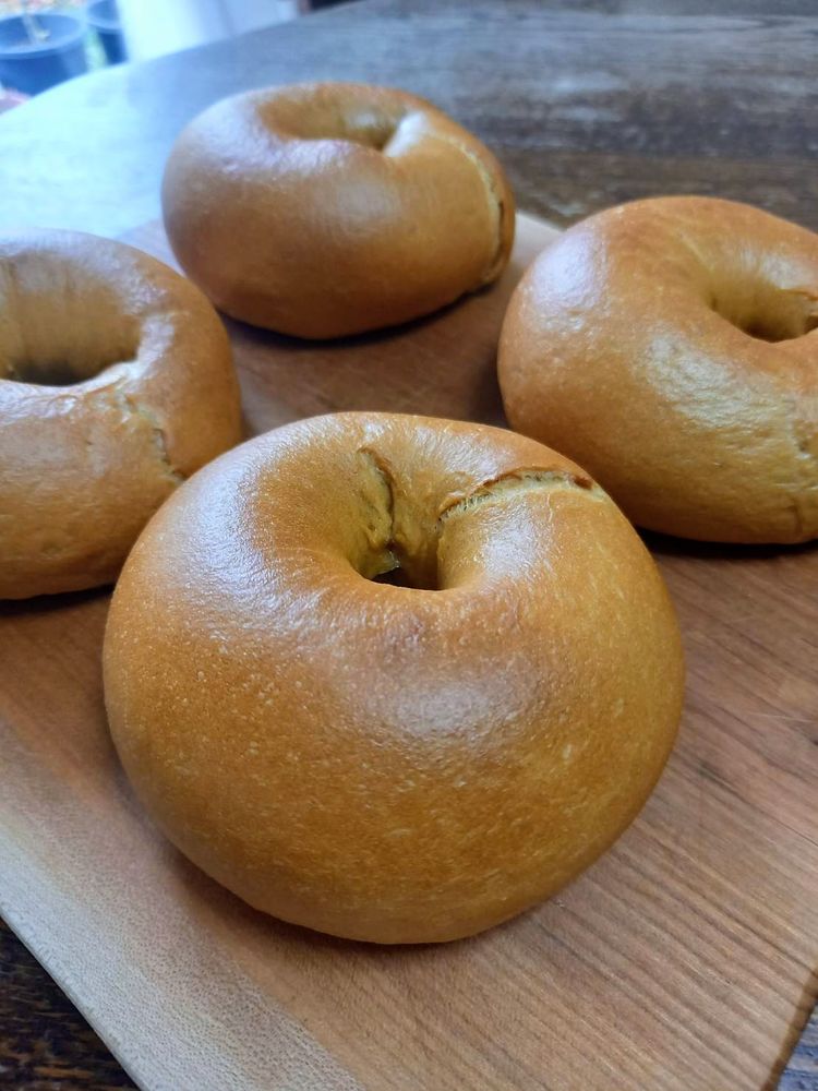 狐色に焼けたベーグル4個が木製ボードにのっている