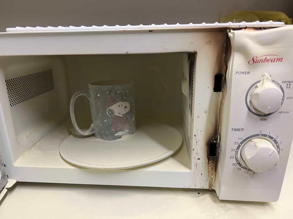A microwave after it caught fire and was hit by a fire extinguisher 