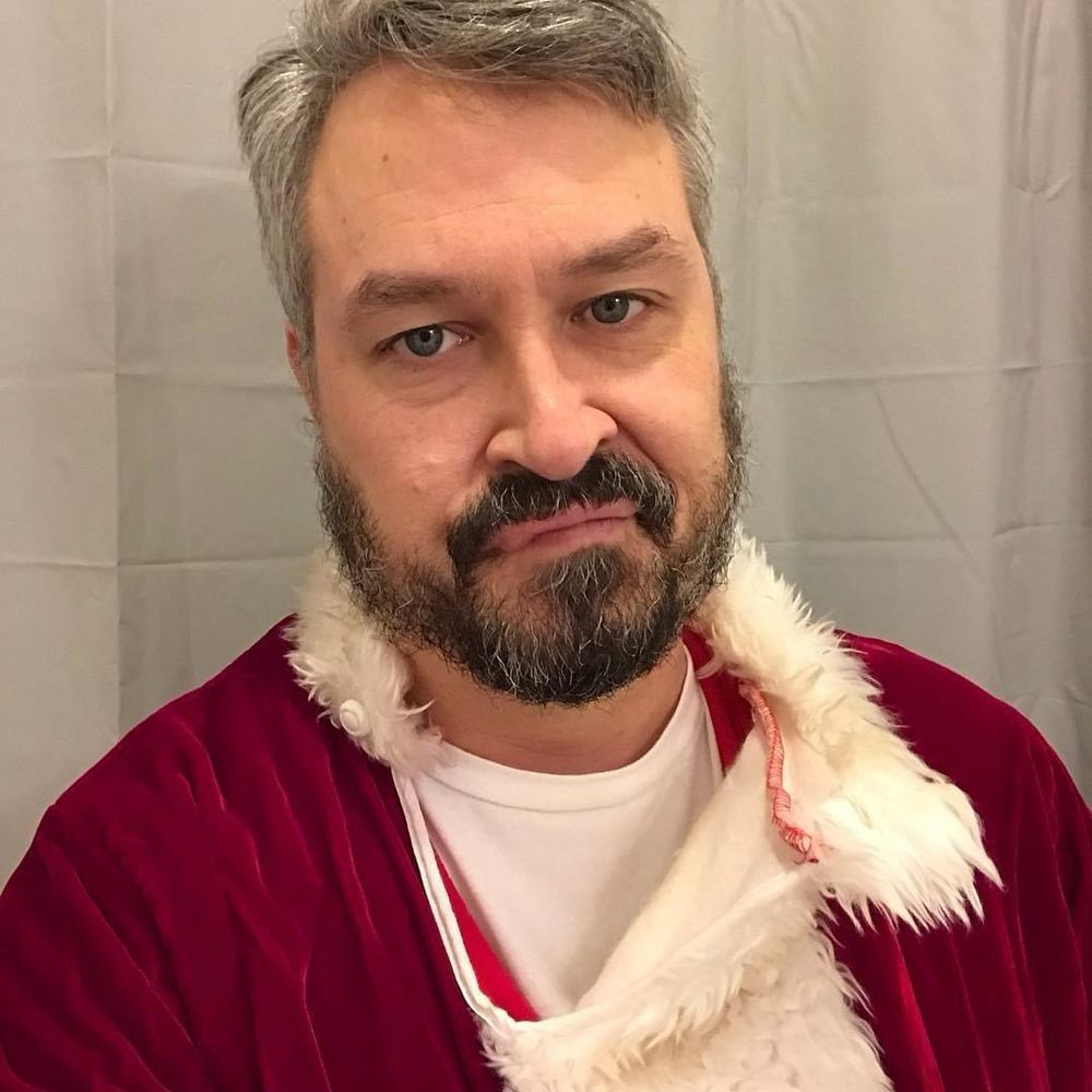 A man who is not happy to be wearing a Santa Clause suit.