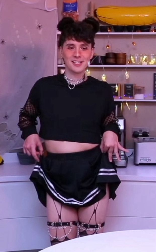 Dan Howell in a black skirt, barely coving his modesty, as well as a black crop top and bear ears.