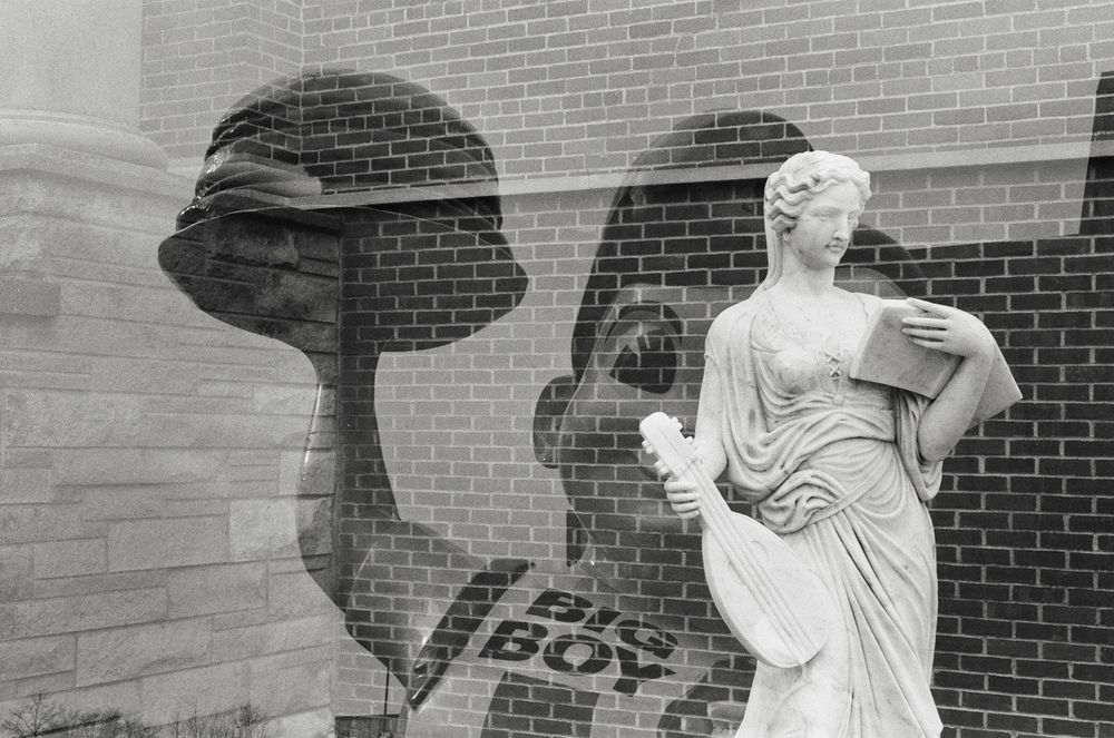 Black and white film double exposure: 1) Big Boy restaurant statue; 2) Classical statue of a woman holding a book and a musical instrument.