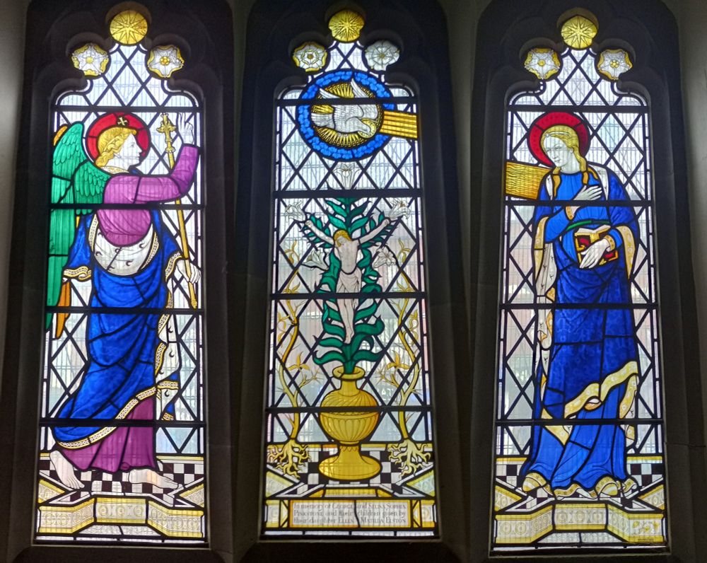Stained glass annunciation scene with a central lily crucifixion.