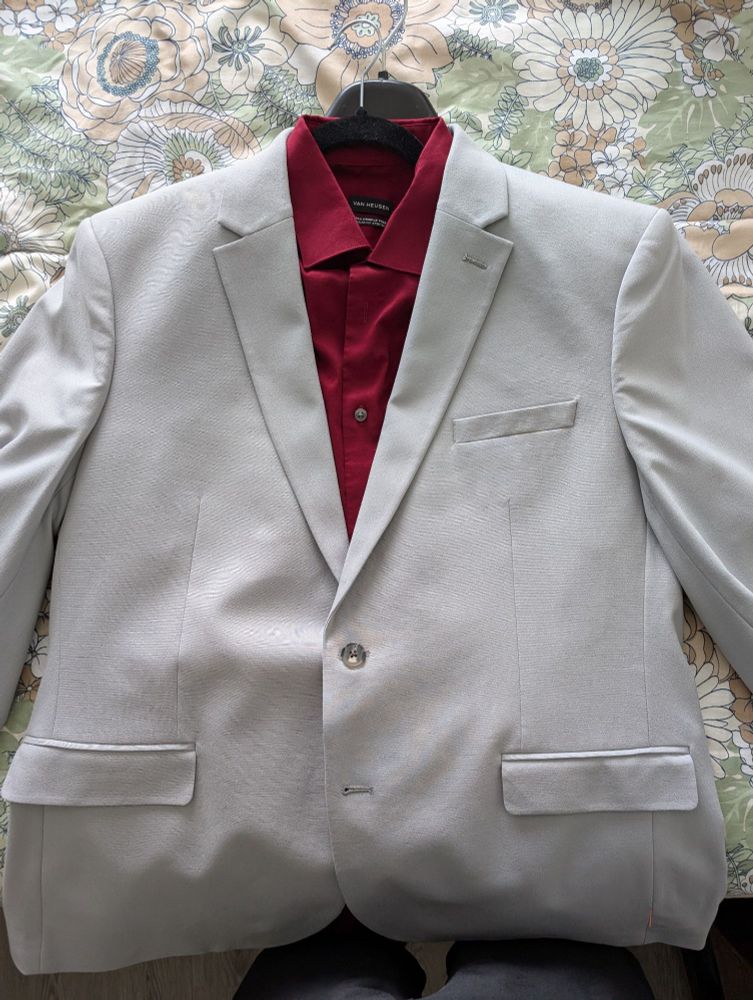 A reflective burgundy dress shirt with a light grey suit buttoned over it.