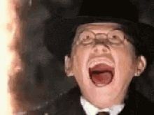 A gif of actor Ronald Lacey's character being melted by a pilar of fire in Raiders of the Lost Ark. He is a pale man wearing glasses and a black hat, his face transitioning from flesh melting to blood and bone (an effective wax practical effect)