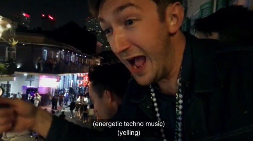 Shane Madej formerly of Buzzfeed Unsolved and now Watcher seemingly in New Orleans watching the street from a balcony. He’s wearing a black jacket with lots of bead necklaces and looks very excited. The picture is labeled “(energetic techno music) (yelling)”