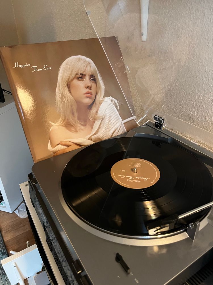 A turntable with a record playing; Billie Eilish’s Happier Than Ever LP jacket is leaning alongside