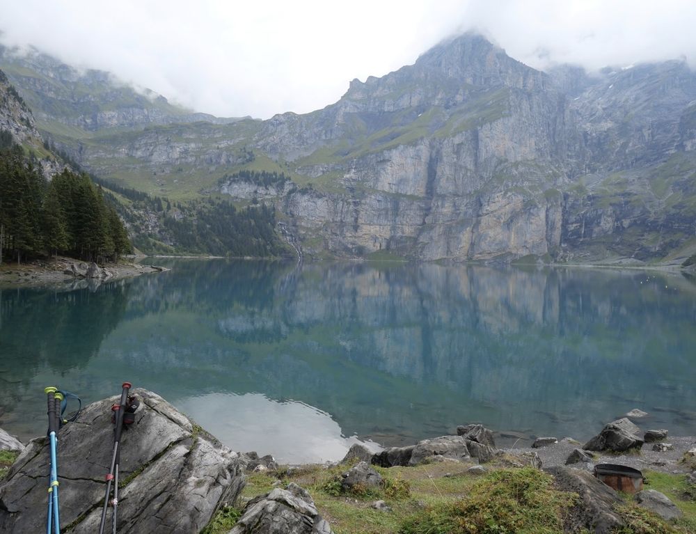 A view of a swiss alpine lake, with light clouds covering the tips of mountains above.