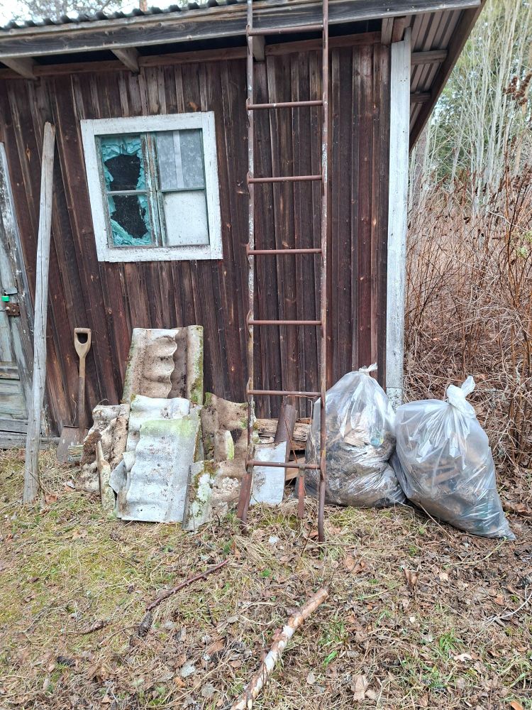 Old shed with broken window. Garbagebags and part of an old roof in front.