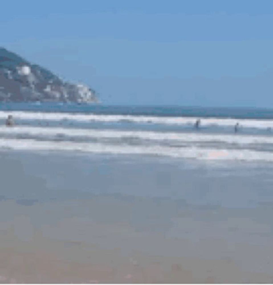 a woman is standing on a beach holding a baby .