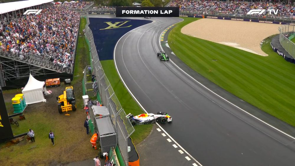 Print da transmissão do Grande Prêmio da Austrália de Fórmula 1. A pista está molhada e um carro branco da equipe Racing Bulls está com a traseira batida contra uma barreira de proteção. Um letreiro da transmissão diz "Formation Lap"