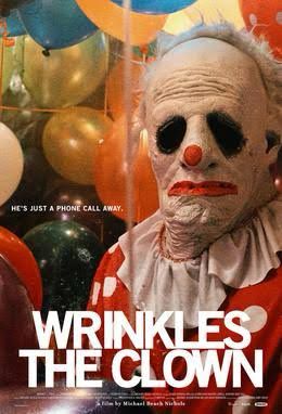 A very wrinkled clown’s face with hollow black eyes. Behind the clown are many balloons. 