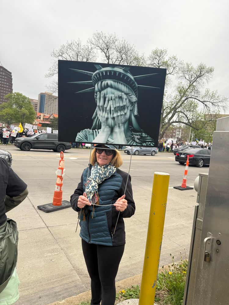 A woman holds a sign depicting the Statue of Liberty weeping with her face in her hands at the Kansas City 50501 Protest on 4/19/25