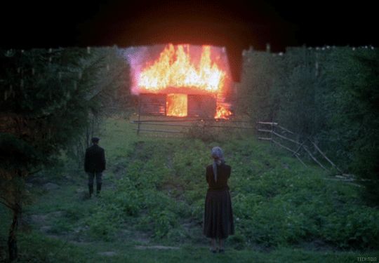 GIF of house burning with two people, backs to the camera, watching from a field in the foreground. From Andrei Tarkovsky's seminal, partially autobiographical 1975 masterpiece Зеркало (MIRROR).
