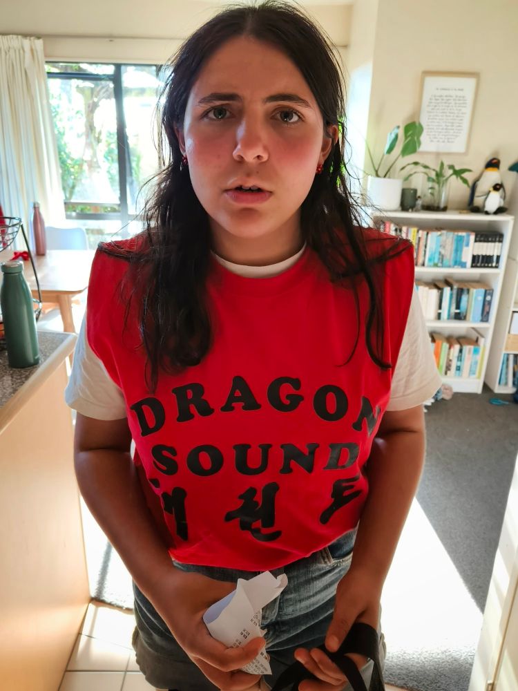 Photo of teen wearing a bright red 'Dragon Sound' t-shirt and a slightly confused expression on her face