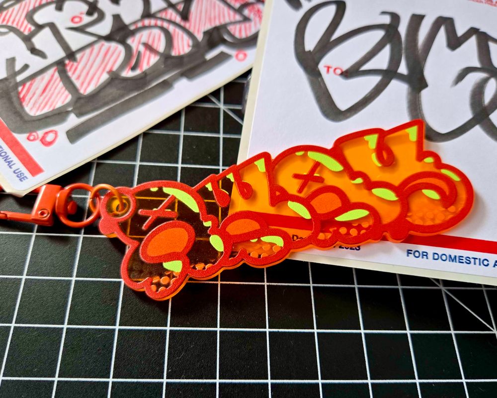 orange graffiti keychain that reads AWAY, by BUGSLAP