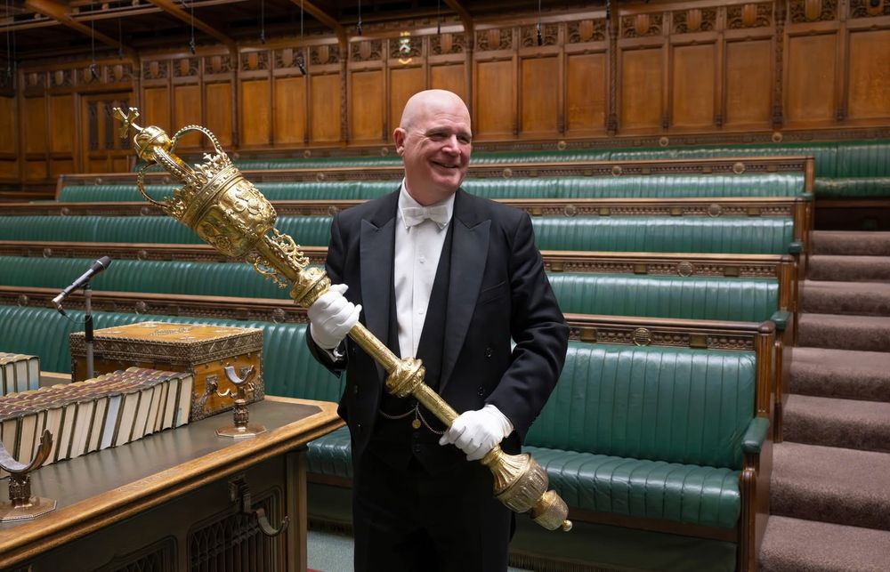 The Sargent of Arms of the House of Commons, dressed in white tie carries the Mace of the House of Commons. It is 5 feet long, gilded, and its head is a crown.