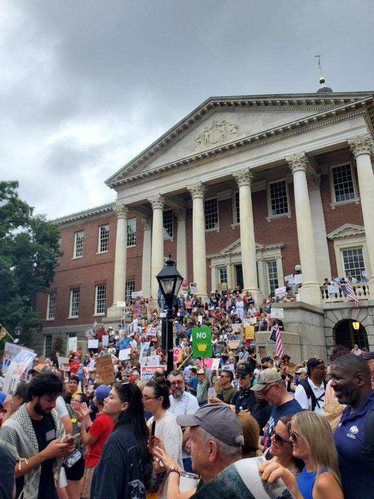 Protestors standing on the steps of the MD state house with signs 