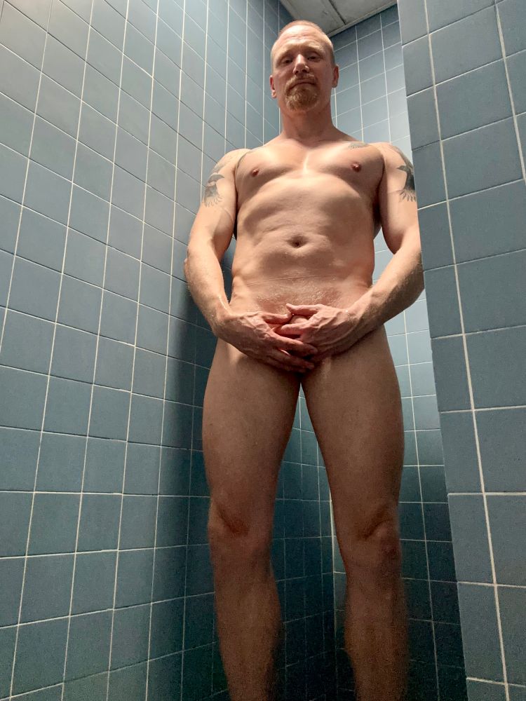 Timer selfie of naked Timo facing the camera, about to have a shower. He’s smiling and covering his dick and nuts.