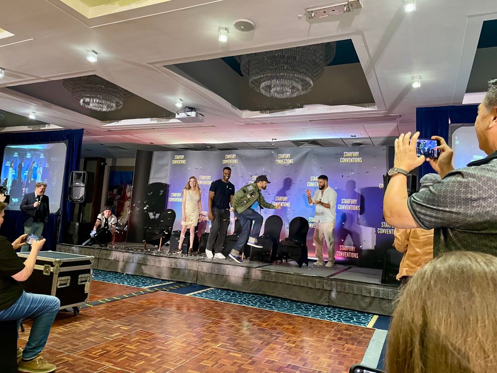 A confetti canon has been blown and the guests are standing and reacting to Jeremy’s dance moves