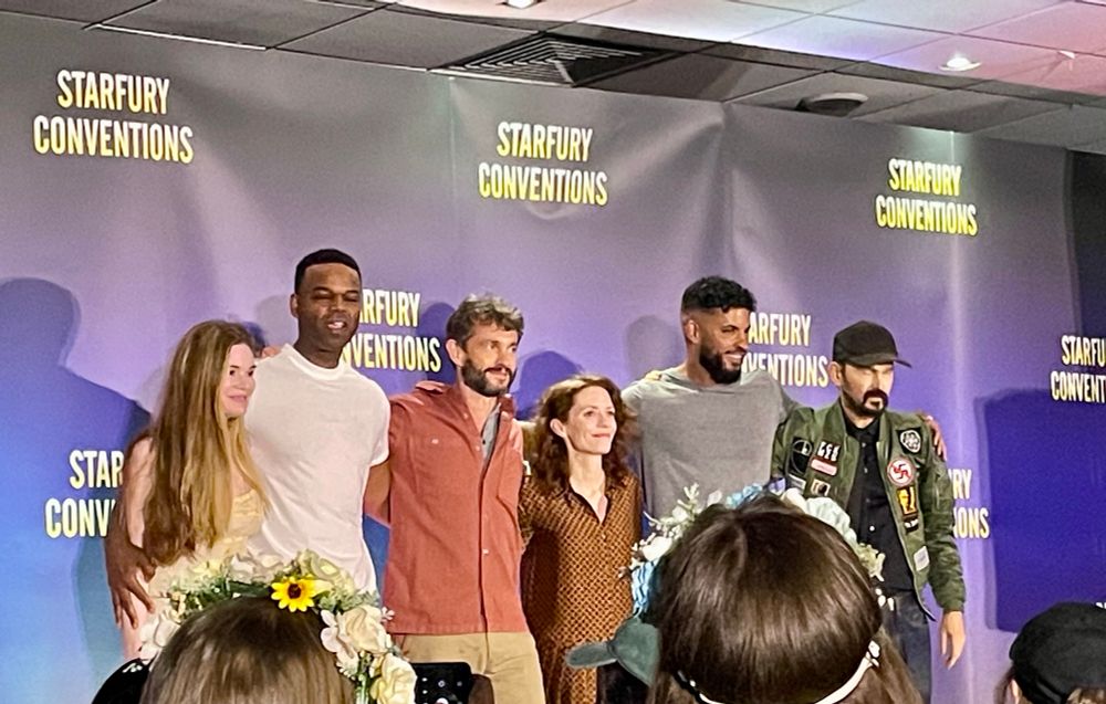 Six actors on stage in a line with a Starfury conventions backdrop. They are: Ellen Muth, Demore Barnes, Hugh Dancy, Lara Jean Chorostecki, Ricky Whitle, and Jeremy Davies. 
