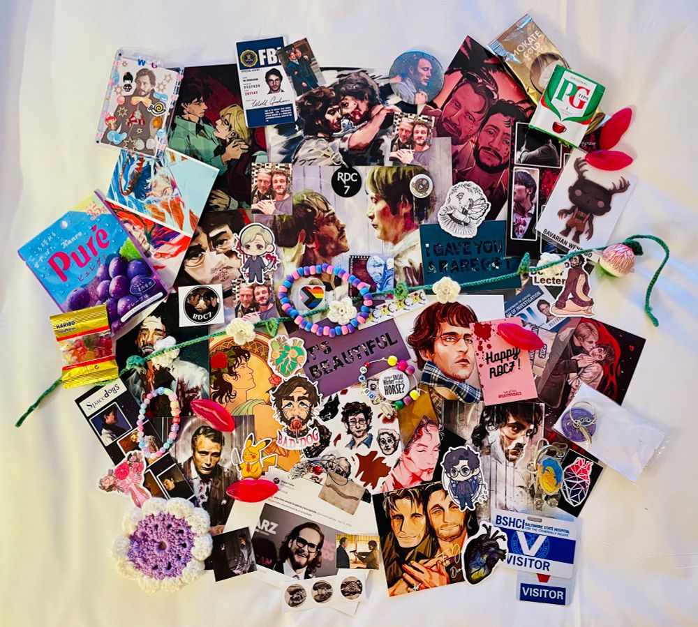An array of colourful art cards, stickers, key- charms crocheted flowers, sweets, bracelets and other goodies all spread out on a bedspread 