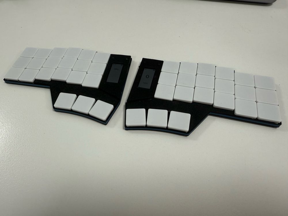 Photo of a split 40% ortholinear keyboard with a screen on each side and white keycaps
