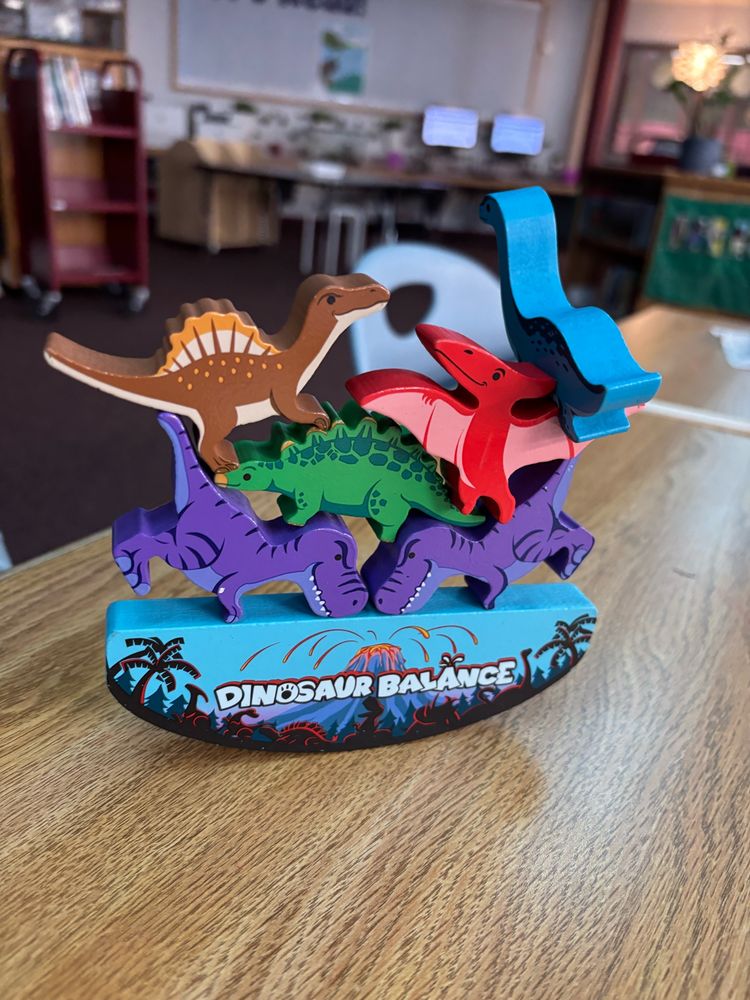 A stack of wooden Dino pieces balance on a rounded foundation. 