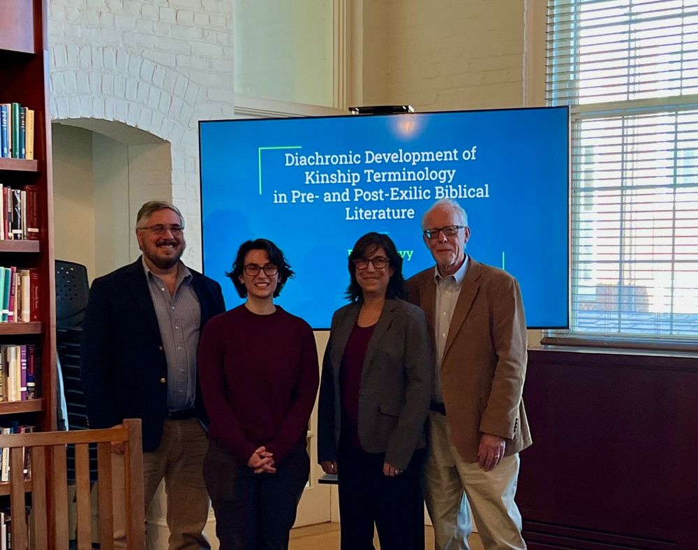 Four people standing in a library in front of a screen that bears the title of the student's MA thesis: "Diachronic Development of Kinship Terminology in Pre- and Post-Exilic Biblical Literature."