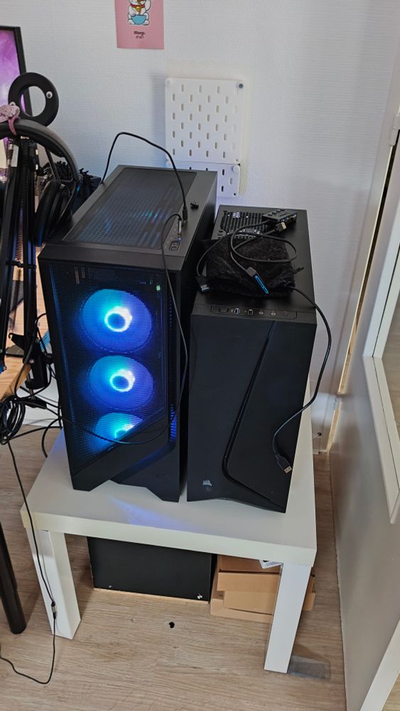 Pic of two black computers next to each other, the left one has 3 big fans with rgb led at the front