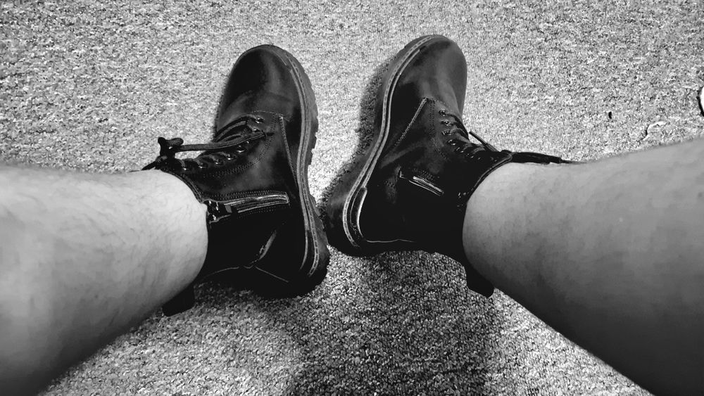 Black short boots with a zipper as a black and white picture. Perspective down on the boots as a viewer equals the view as the wearer