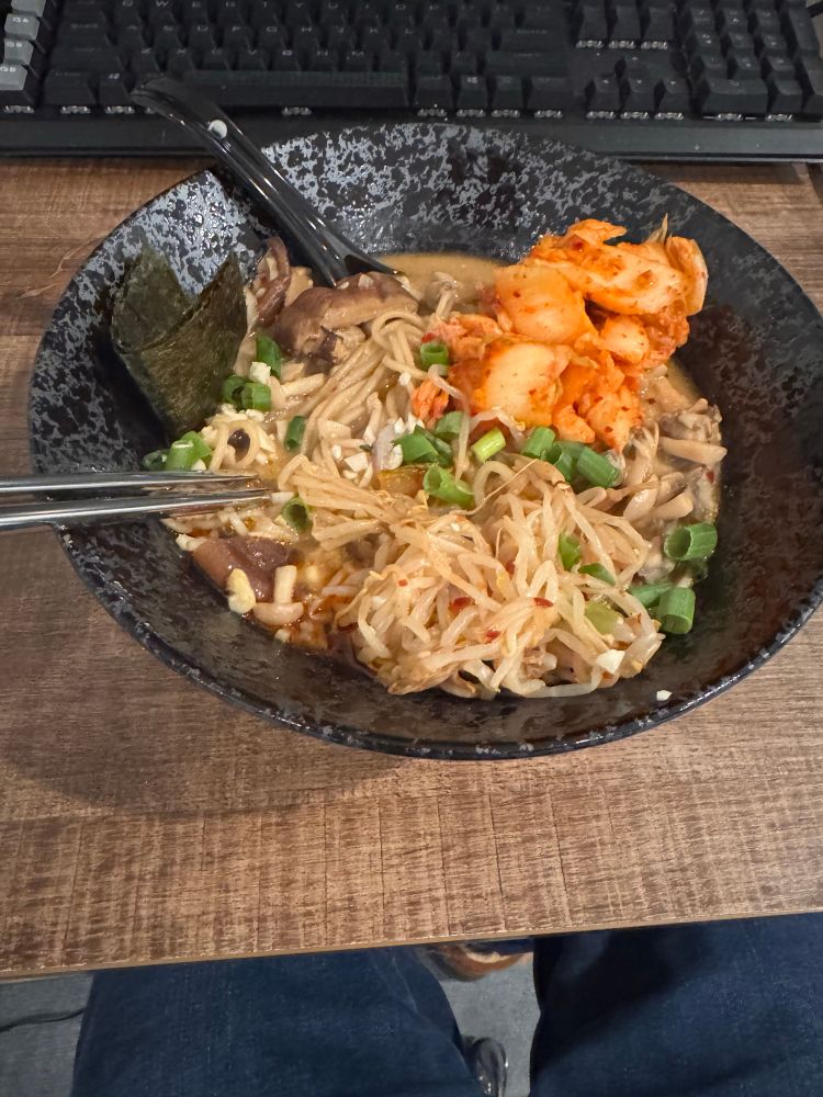 Bowl of vegan ramen with mushrooms, scallions, spicy bean sprout salad, kimchi, and nori