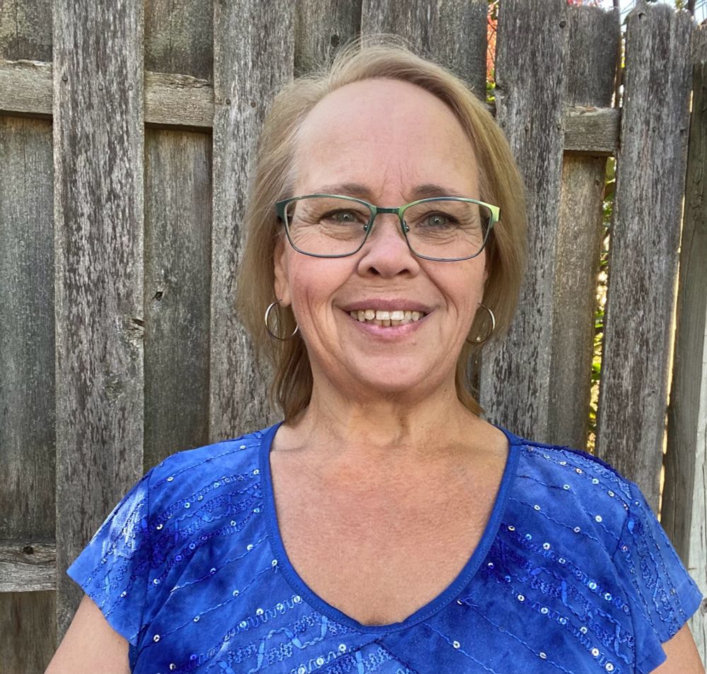 Picture of a woman in a blue shirt in front of a fence