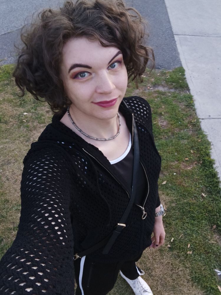 Me outside in a black mesh hoodie, black sports bra and track pants