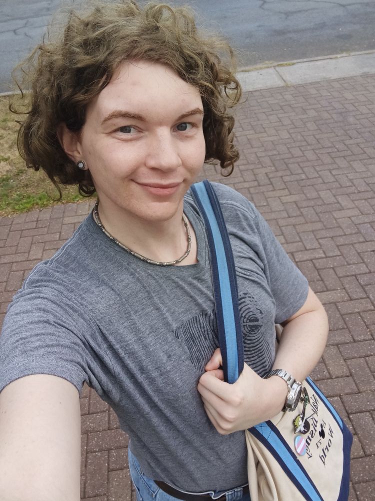 I'm not wearing makeup but my tits are poking out of my t-shirt and I found a trans flag pin for my tote bag