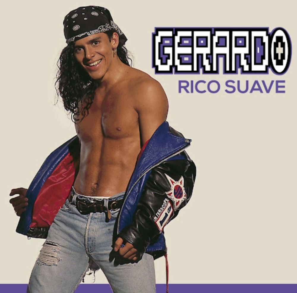 Musician Rico Suave, he is shirtless with a colorful leather jacket down around his forearms. He is wearing shredded washed blue jeans and a black bandana to hold back his lustrous locks of curly hair