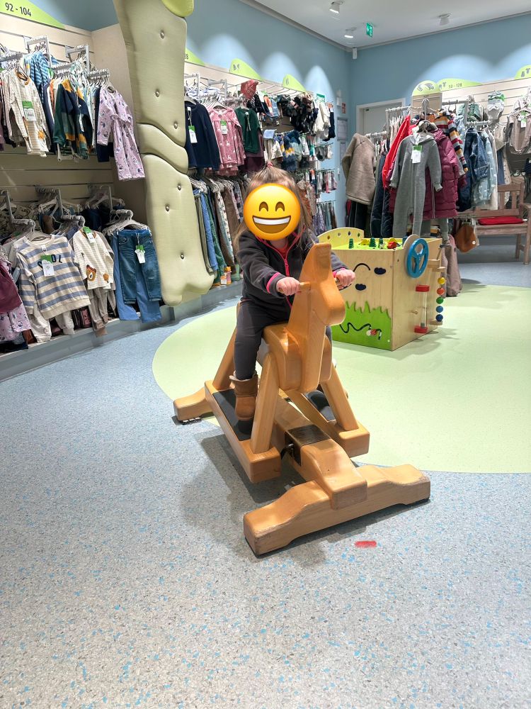 Ein kleines Mädchen sitzt auf einem Schaukelpferd im dm-Markt