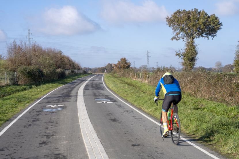 Photo : Arnaud Loubry. Nous pouvons voir un cycliste sur le Réseau express vélo dans un paysage de campagne.