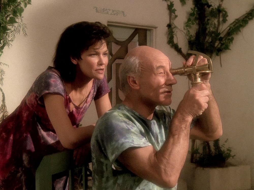 still from The Inner Light. Picard (as Kamin) looks through a small telescope as his wife Eilen looks on