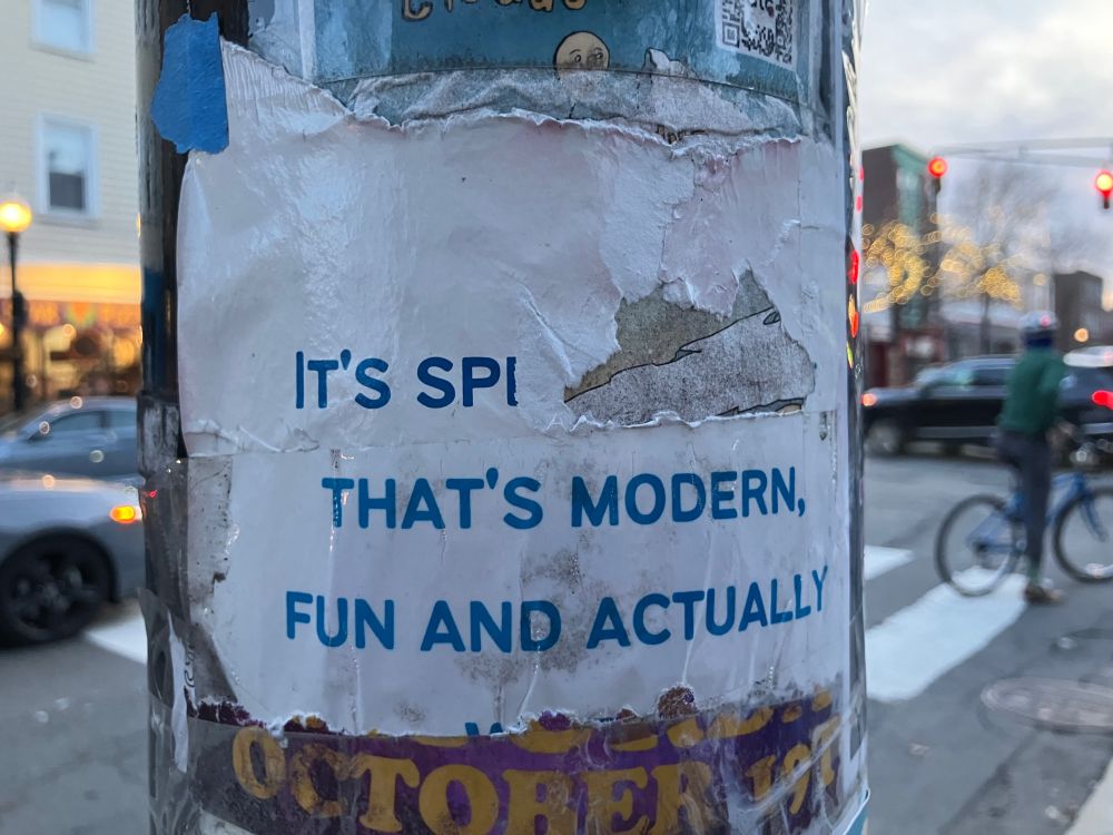 Picture of a lamppost with a torn flyer that reads

IT'S SPI [tear in the paper]
THAT'S MODERN
FUN AND ACTUALLY
[the bottom of the flyer is torn off]