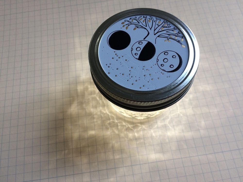 Picture of a cut-glass mason jar with a PCB for its lid, glowing