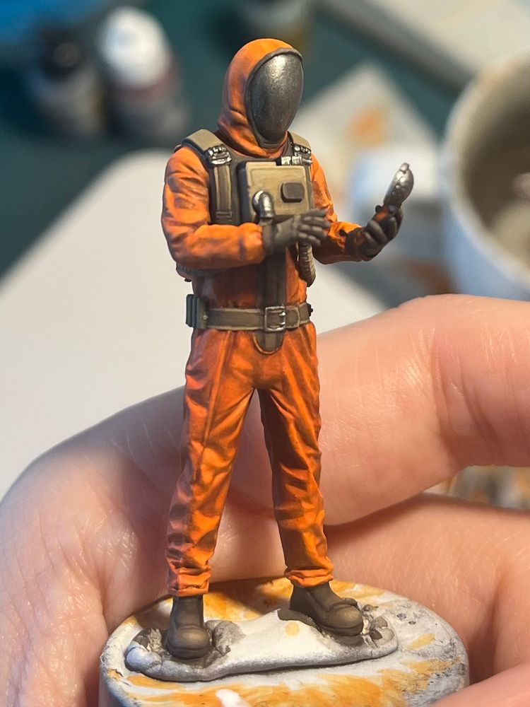 1/35 miniature of an Ecologist from the stalker games. He wears a orange protective suit with reflective visor and looks at a detector