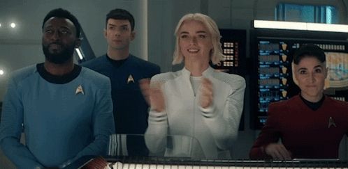 a group of people are standing in front of a computer screen and one of them has the letter a on his shirt