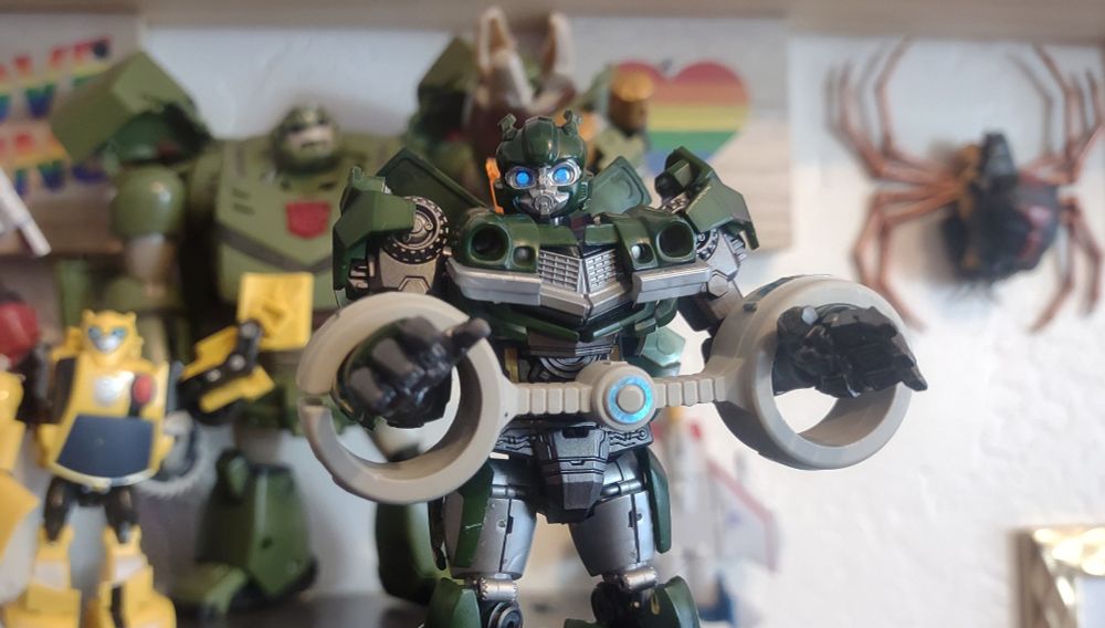 Wasp in stasis cuffs, while Bee and Bulkhead wave him goodbye and a certain spider hangs on the wall.