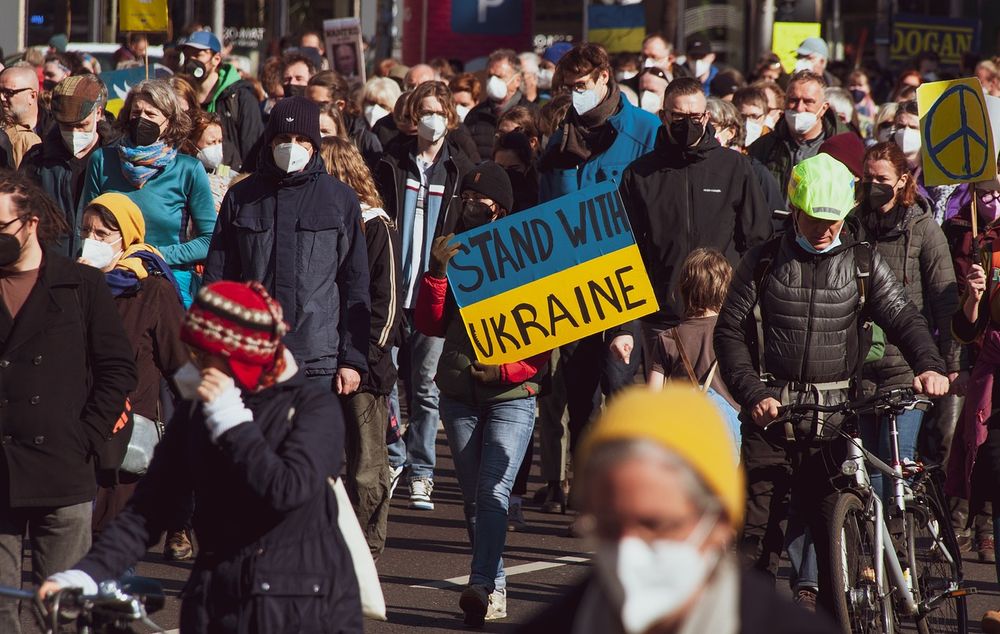 photo of a protest, one poster reads 'stand with ukraine'